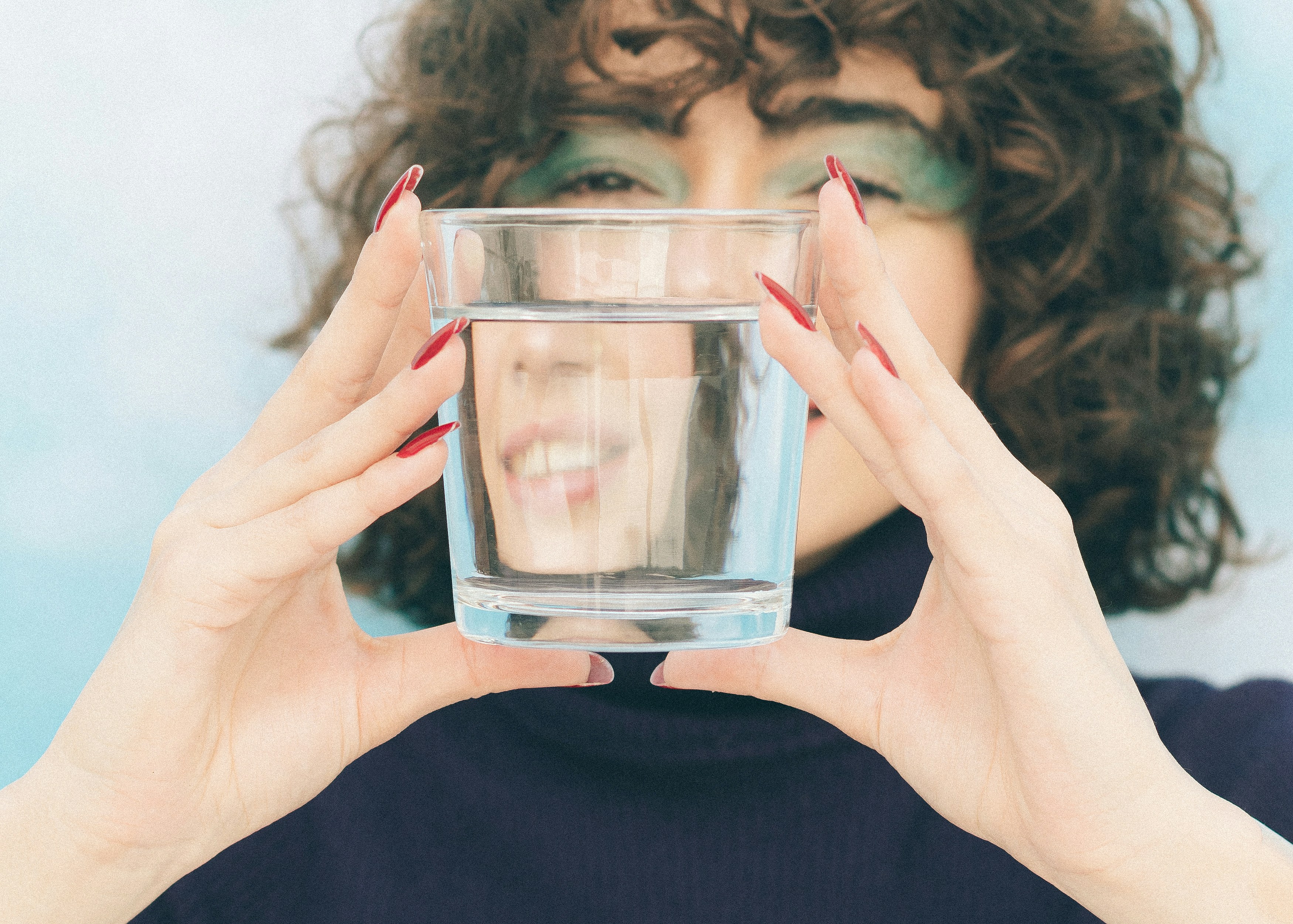 person looking concerned at a glass of water - pfas exposure symptoms