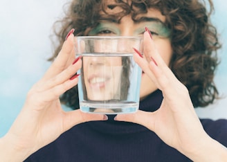A woman covering her face with a glass of water