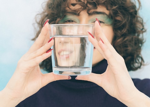 A woman covering her face with a glass of water