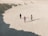 A group of people standing on top of a sandy beach