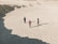 A group of people standing on top of a sandy beach