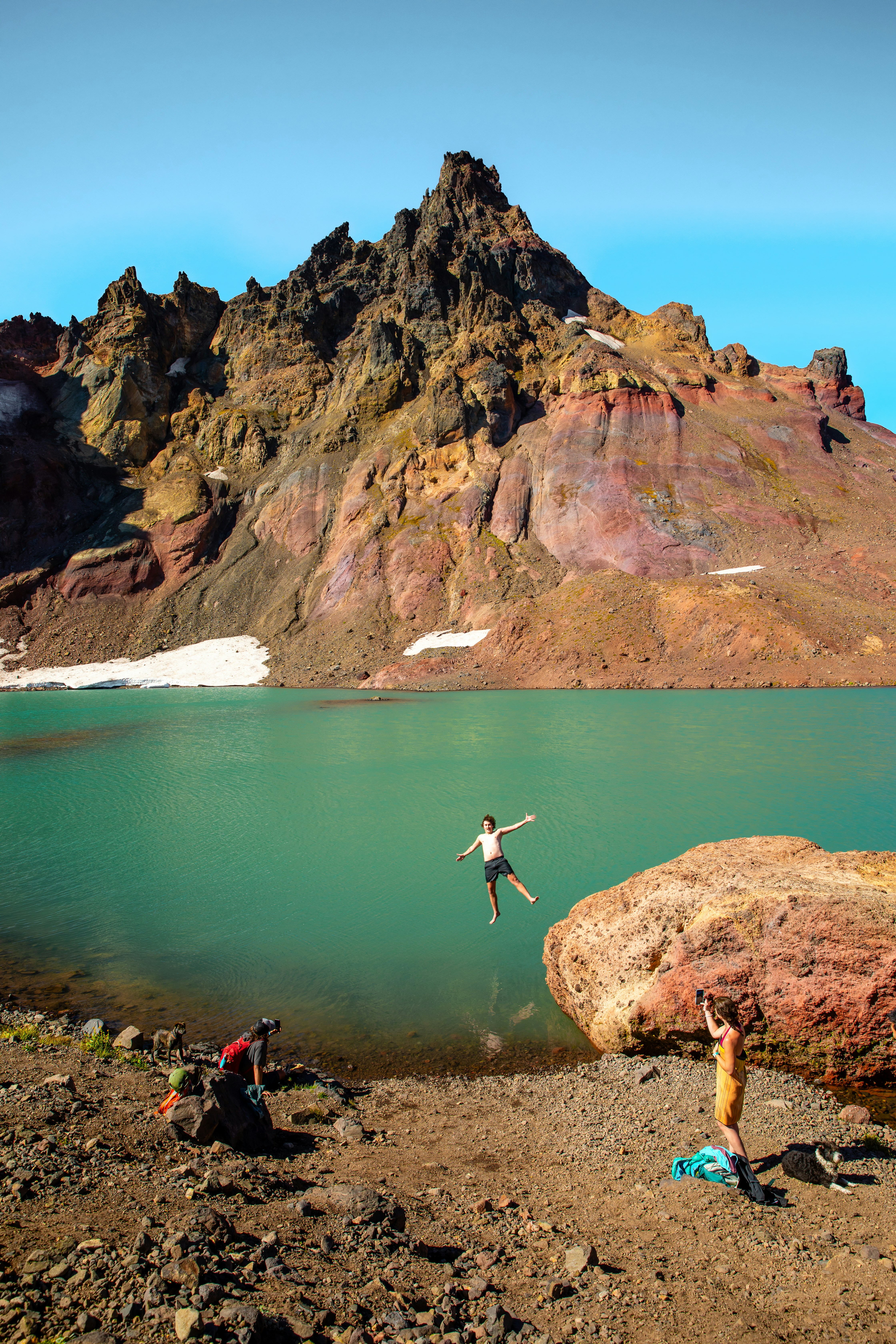 A group of people standing on top of a mountain next to a lake