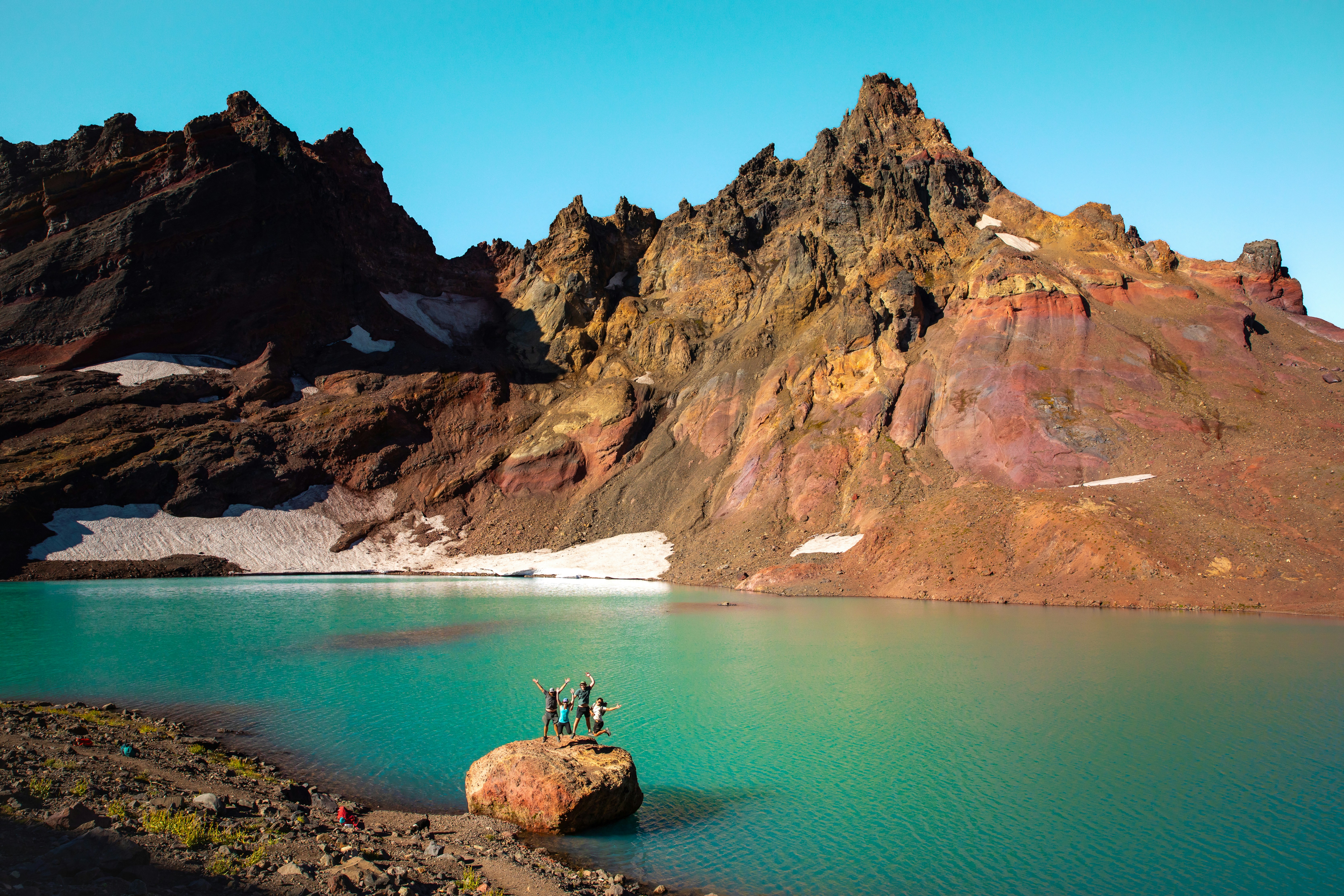 A couple of people standing on top of a mountain next to a lake