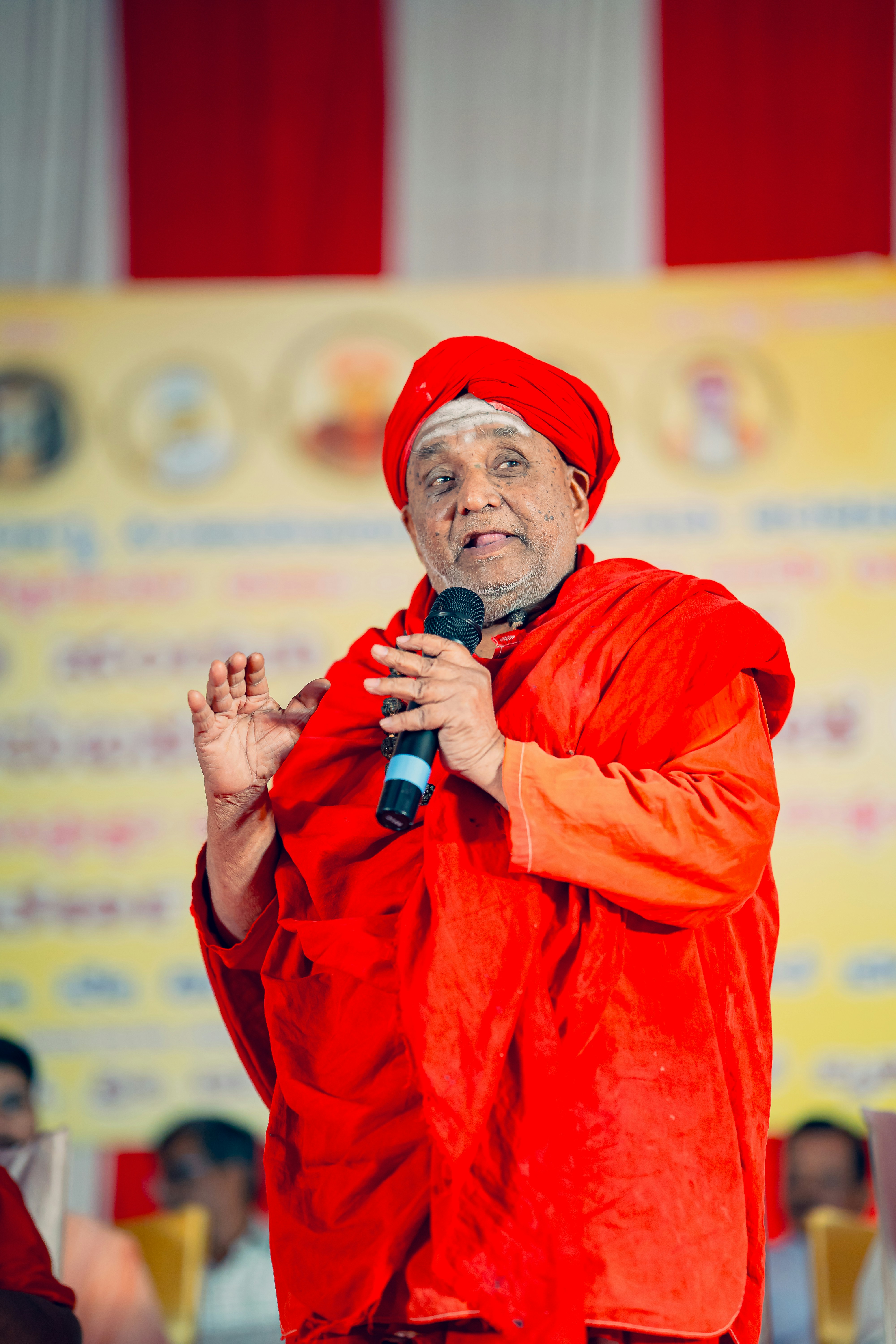 Seorang pria berpakaian merah berbicara ke mikrofon