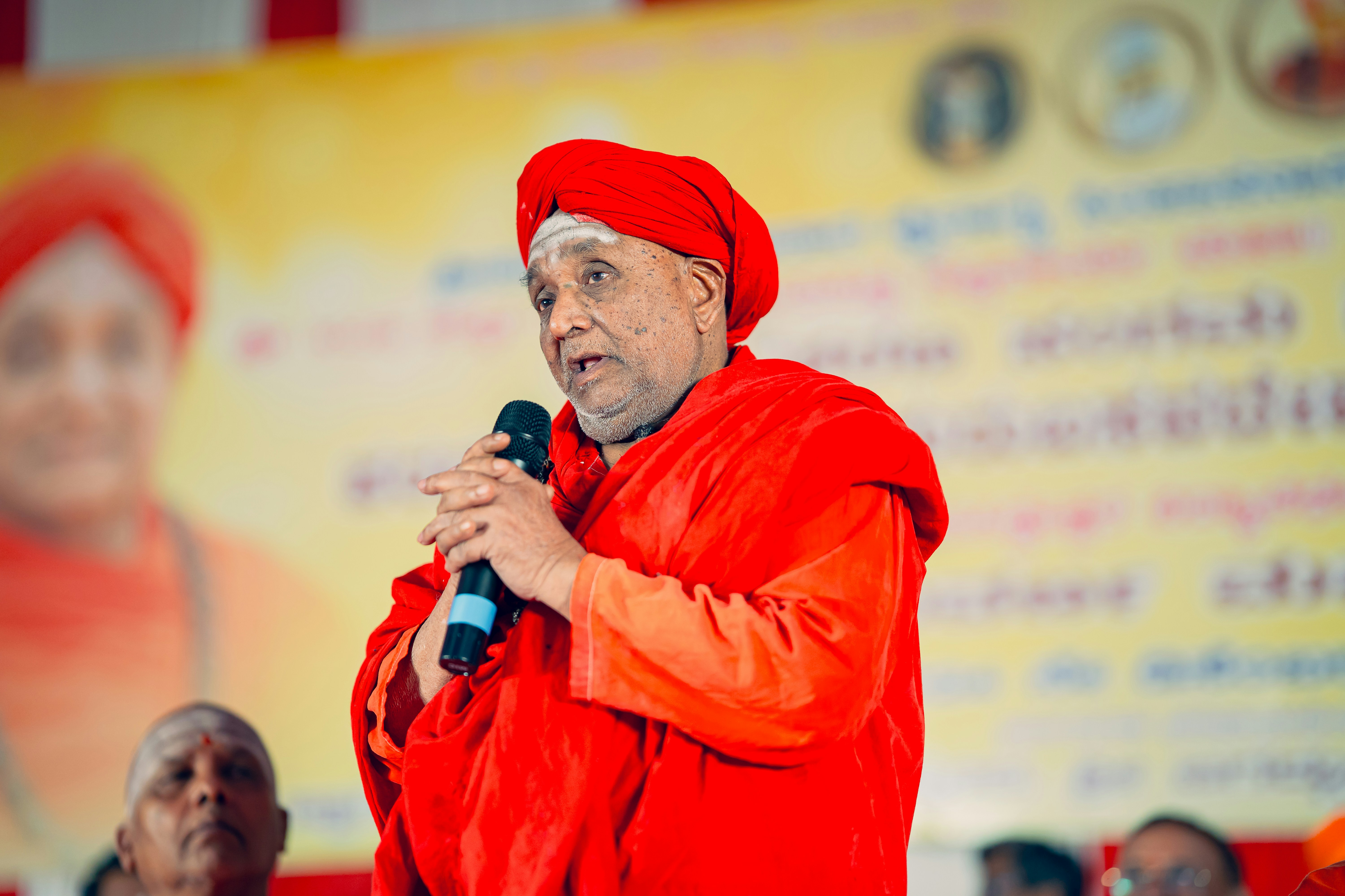 A man in a red turban speaking into a microphone
