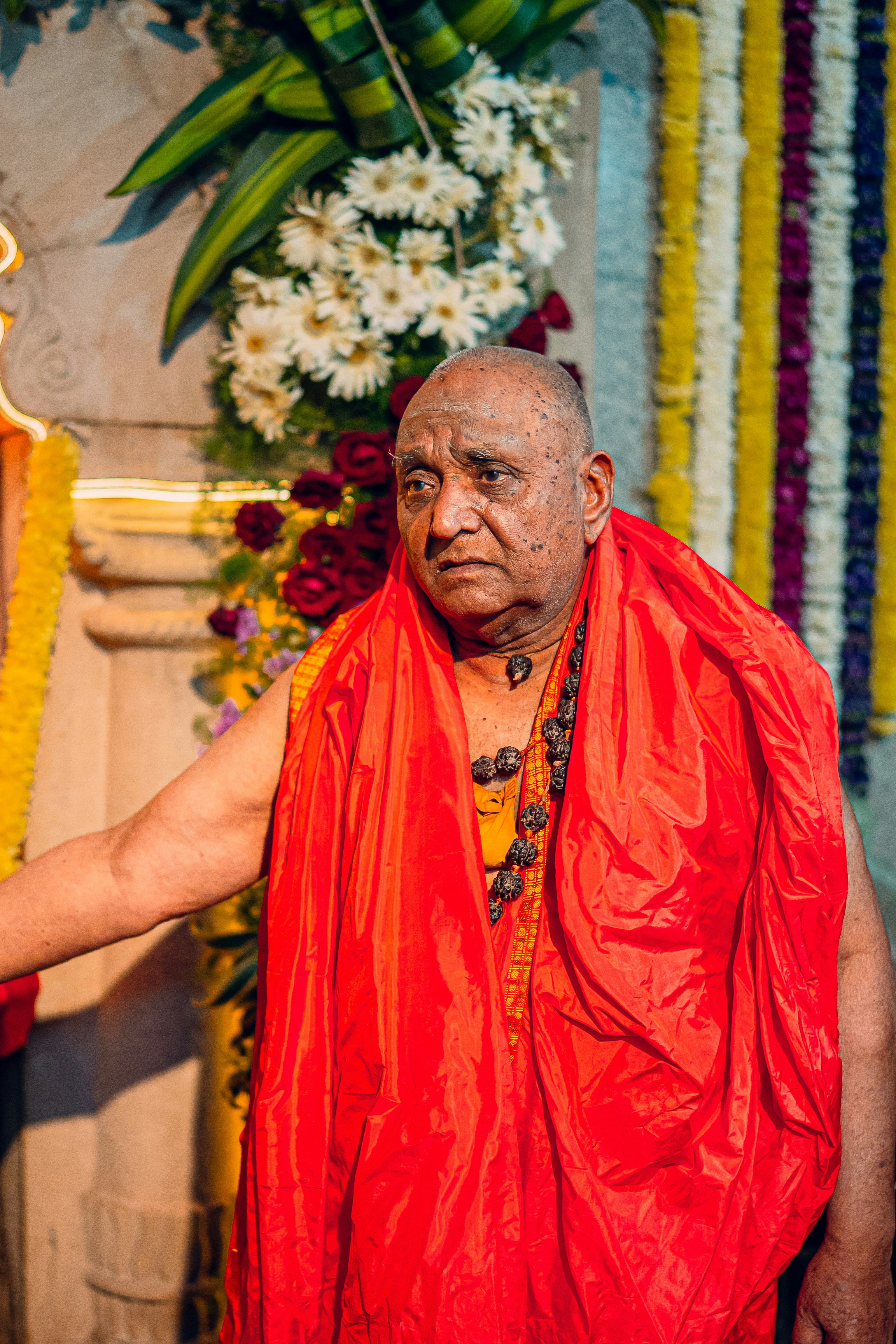 A man in a red robe standing next to a statue