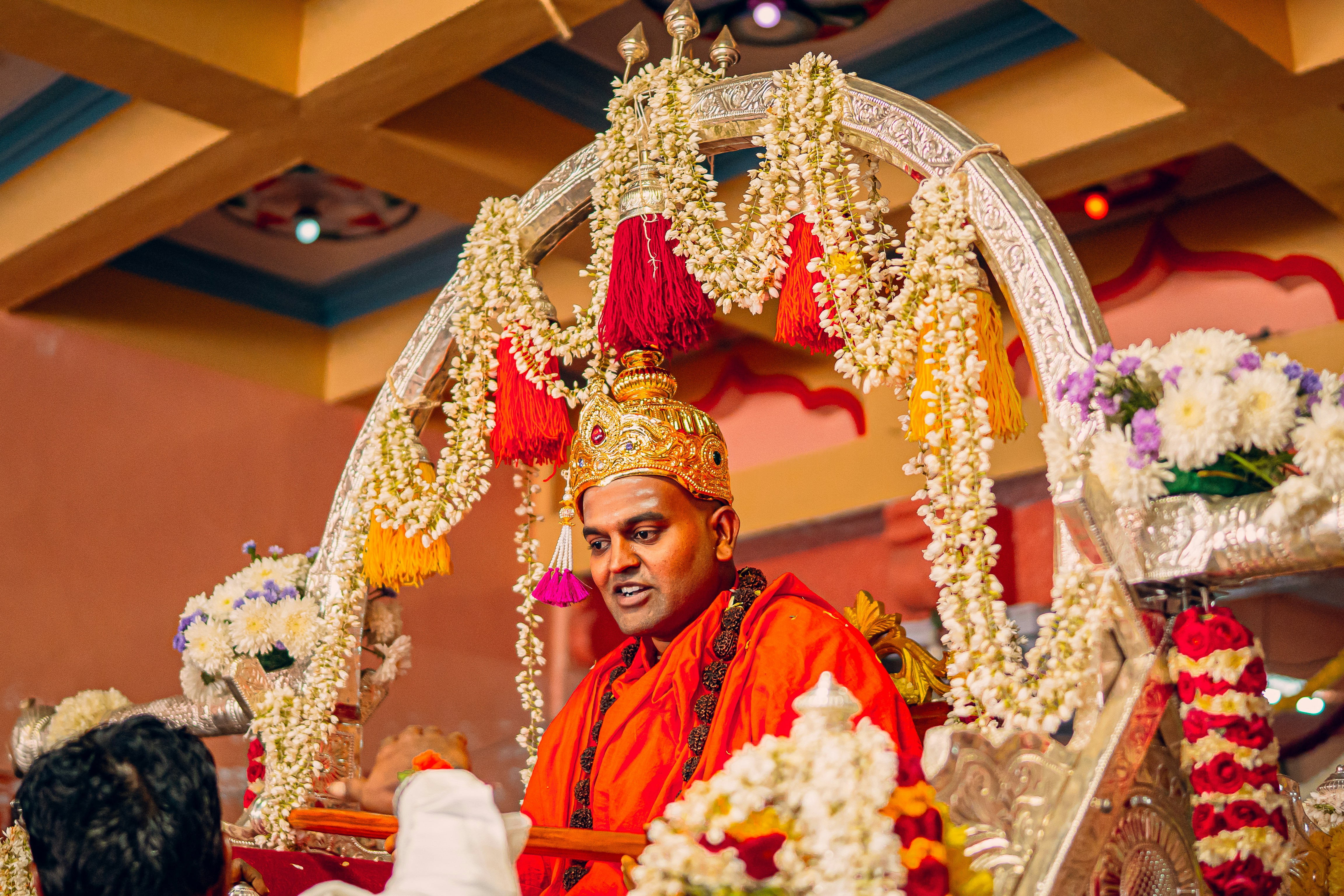A man dressed in an orange outfit sitting on a stage