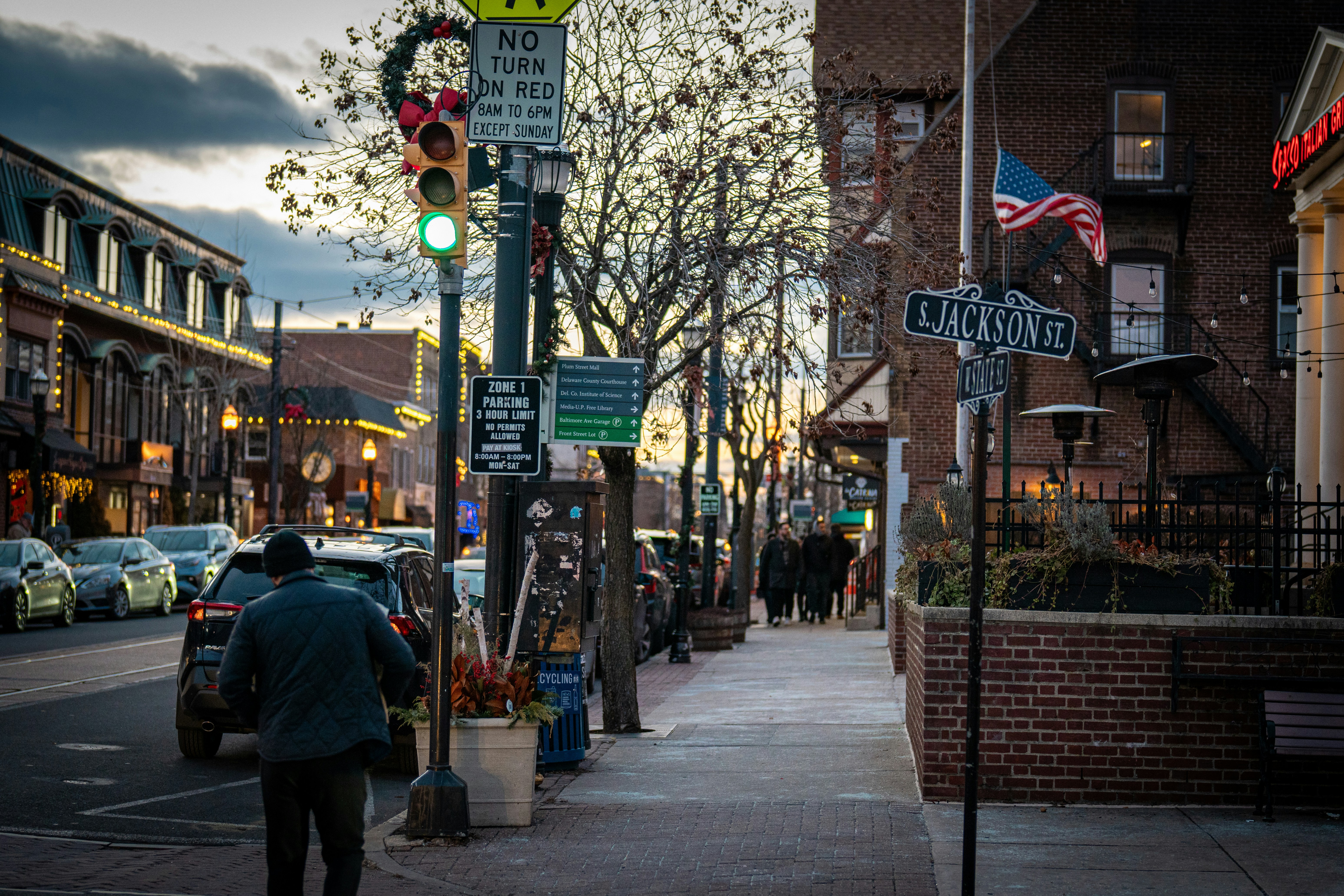 Un hombre caminando por una calle junto a un semáforo