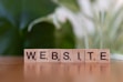 A wooden block spelling the word website on a table