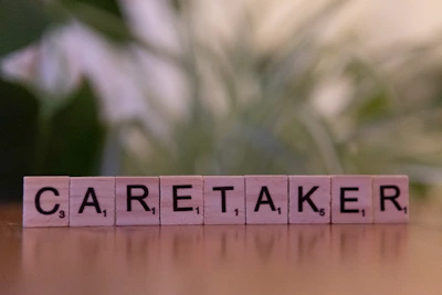 A wooden block spelling carettaker on a table