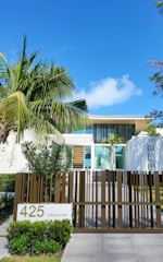 A house with a fence and palm trees in front of it