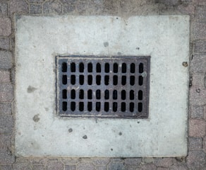 A grate on the side of a brick wall