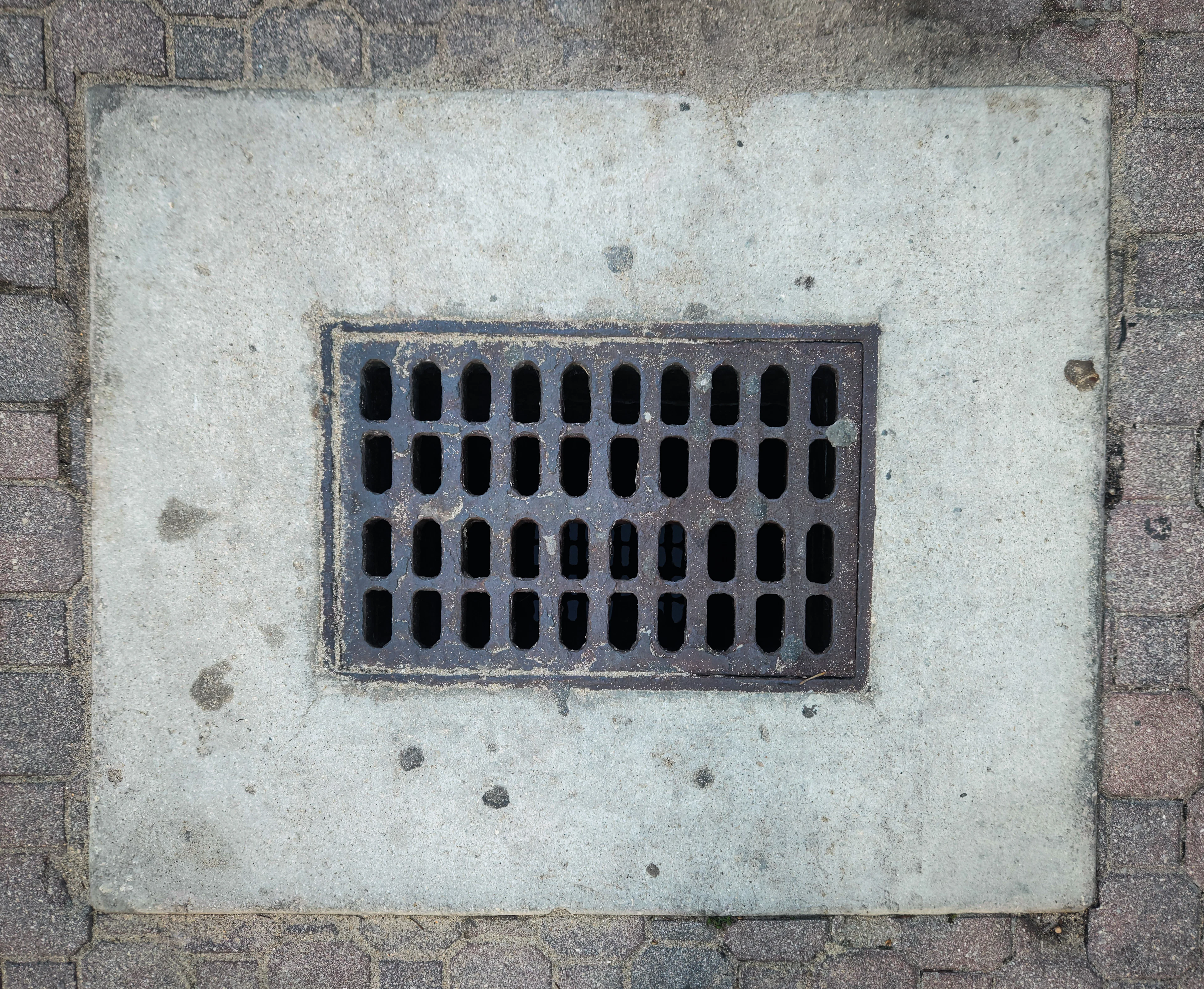 Drain grate beside a brick wall