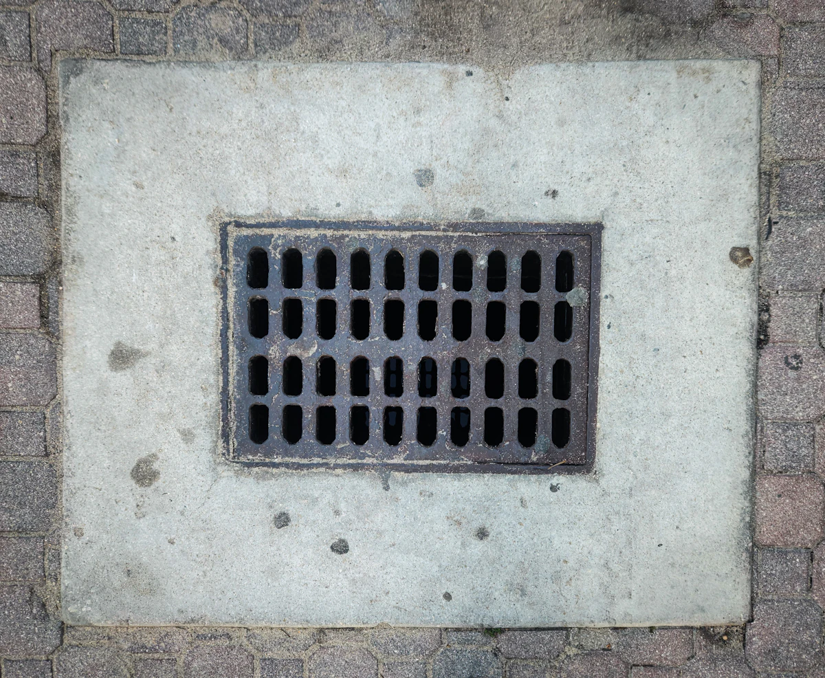 Drainage gully grate set into a wall being inspected for repair