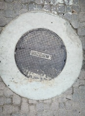 A manhole cover on a brick sidewalk