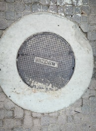 A manhole cover on a brick sidewalk