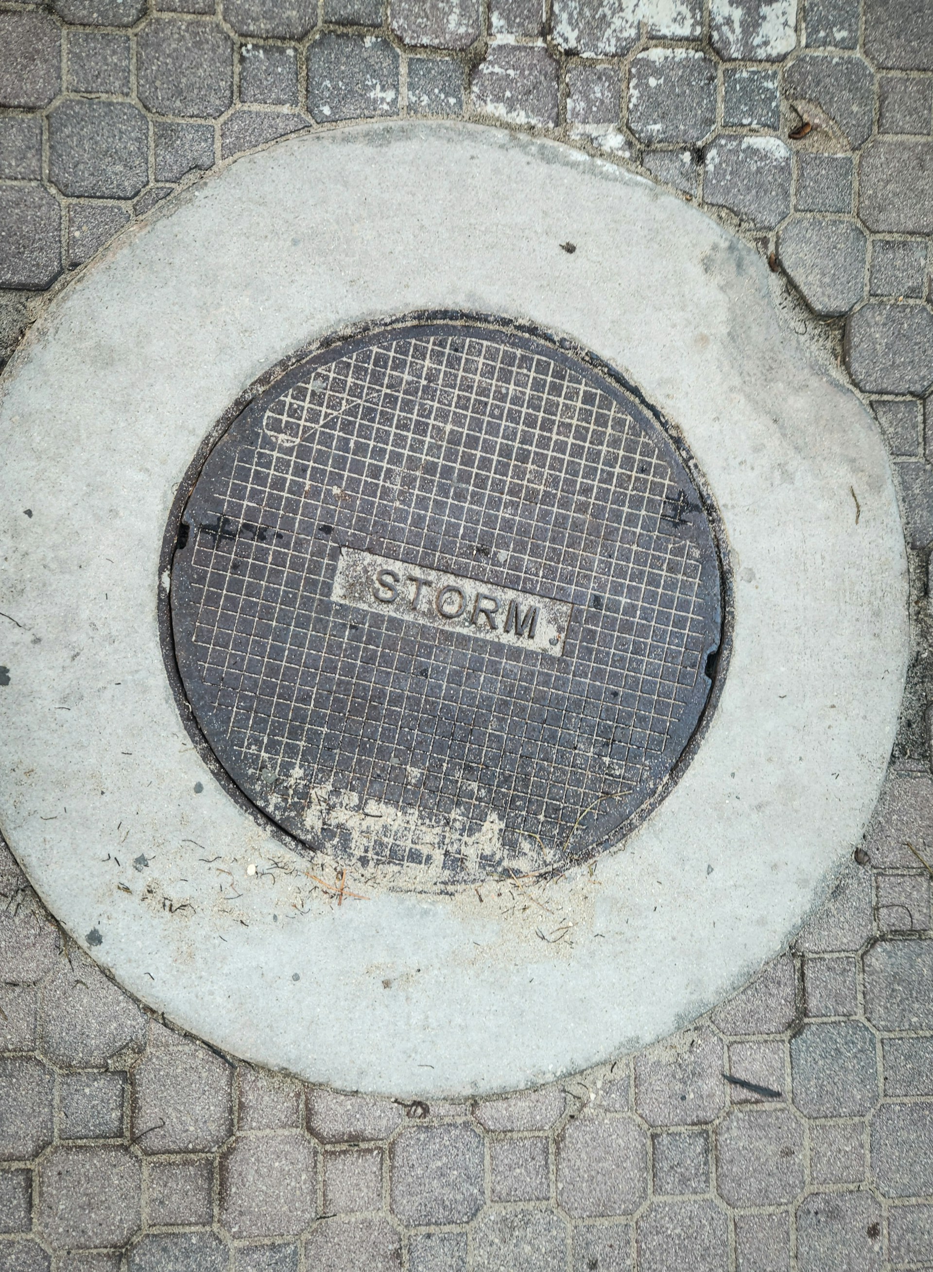 A manhole cover on a brick sidewalk