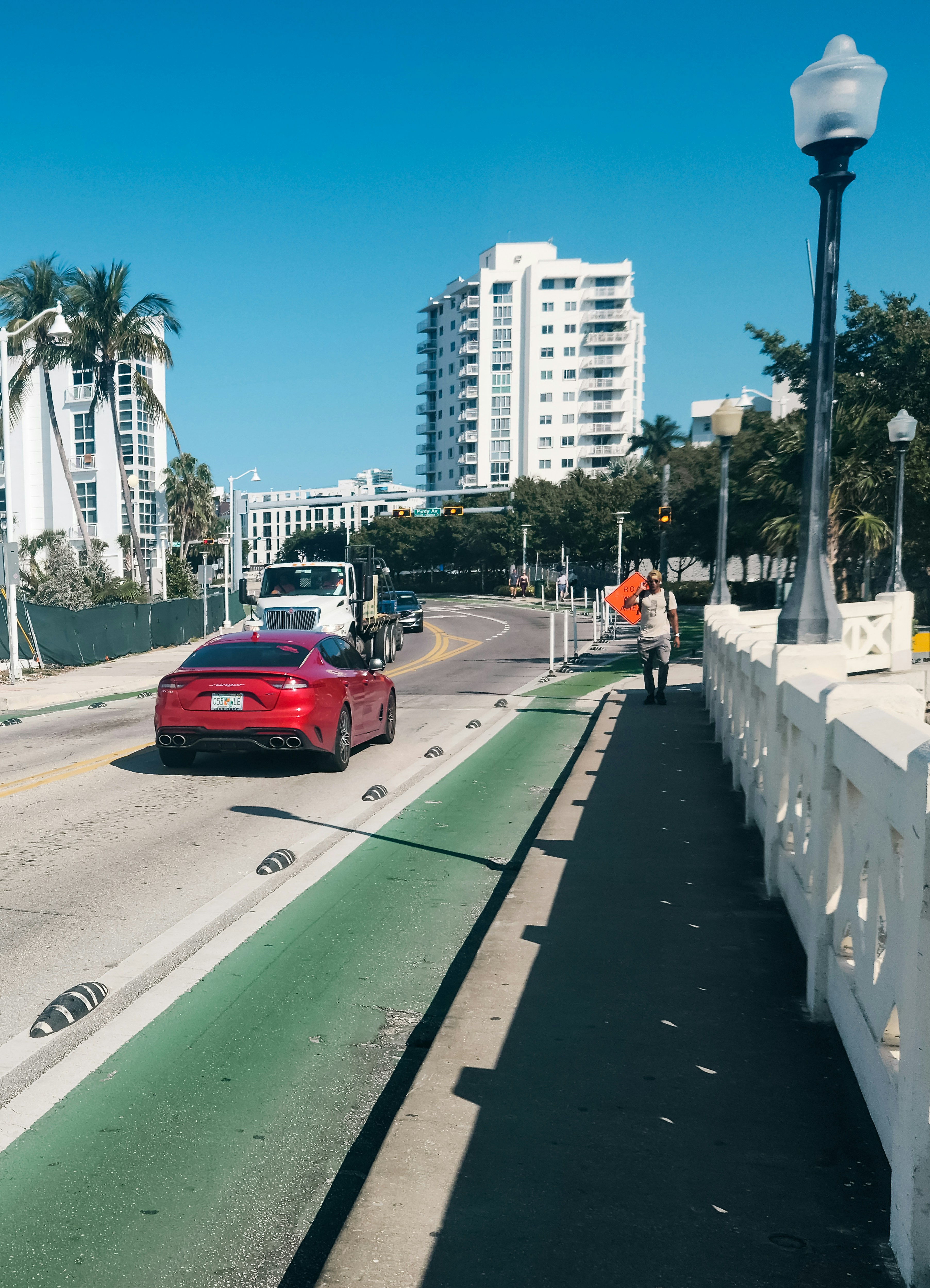 Um carro vermelho dirigindo por uma rua ao lado de prédios altos