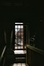A dark hallway with a window and railing