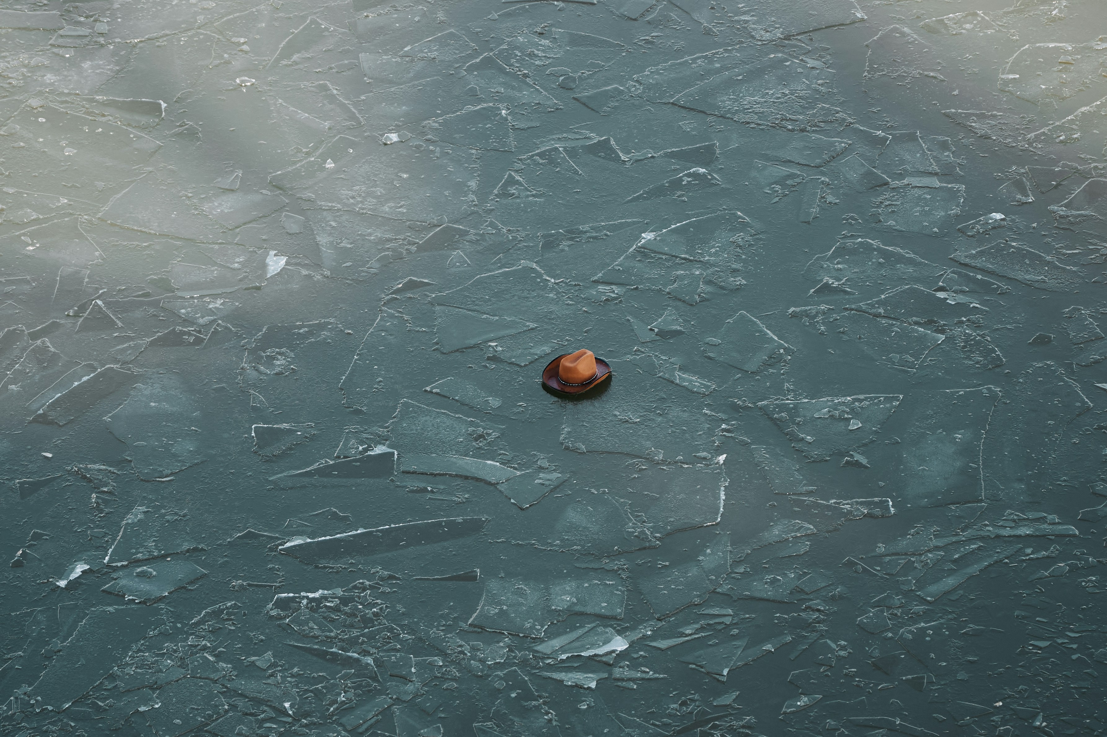 An orange is sitting on a frozen surface