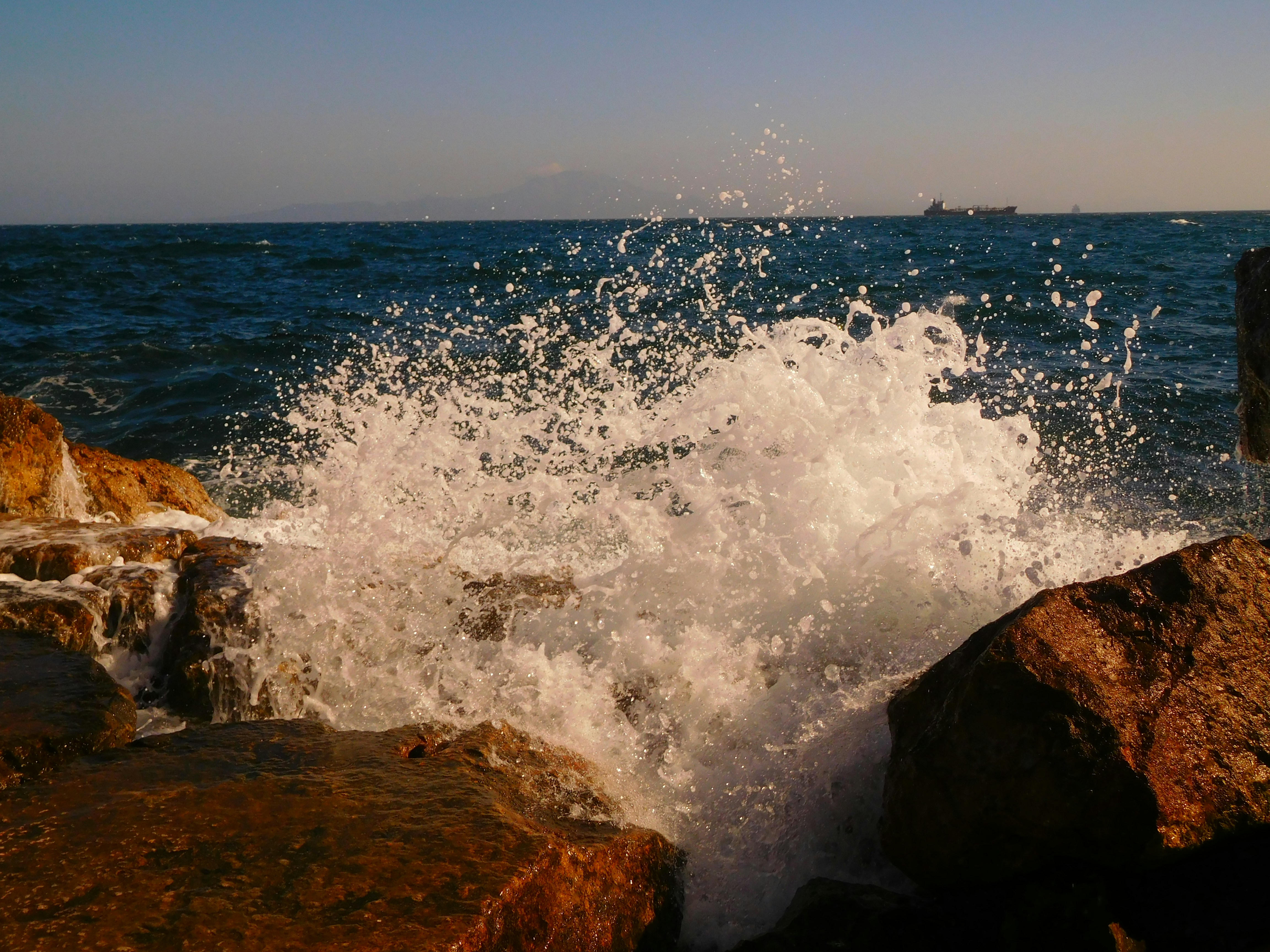 A wave crashes against the rocks at the beach