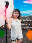 A woman holding an umbrella in front of a fence