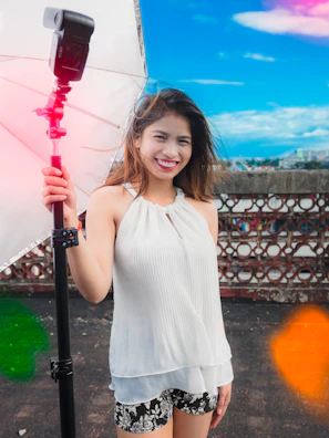 A woman holding an umbrella in front of a fence