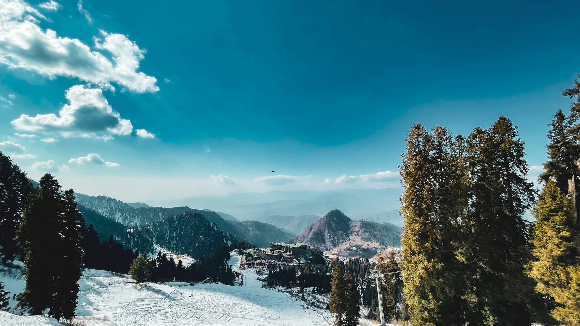 A snow covered ski slope with trees in the foreground