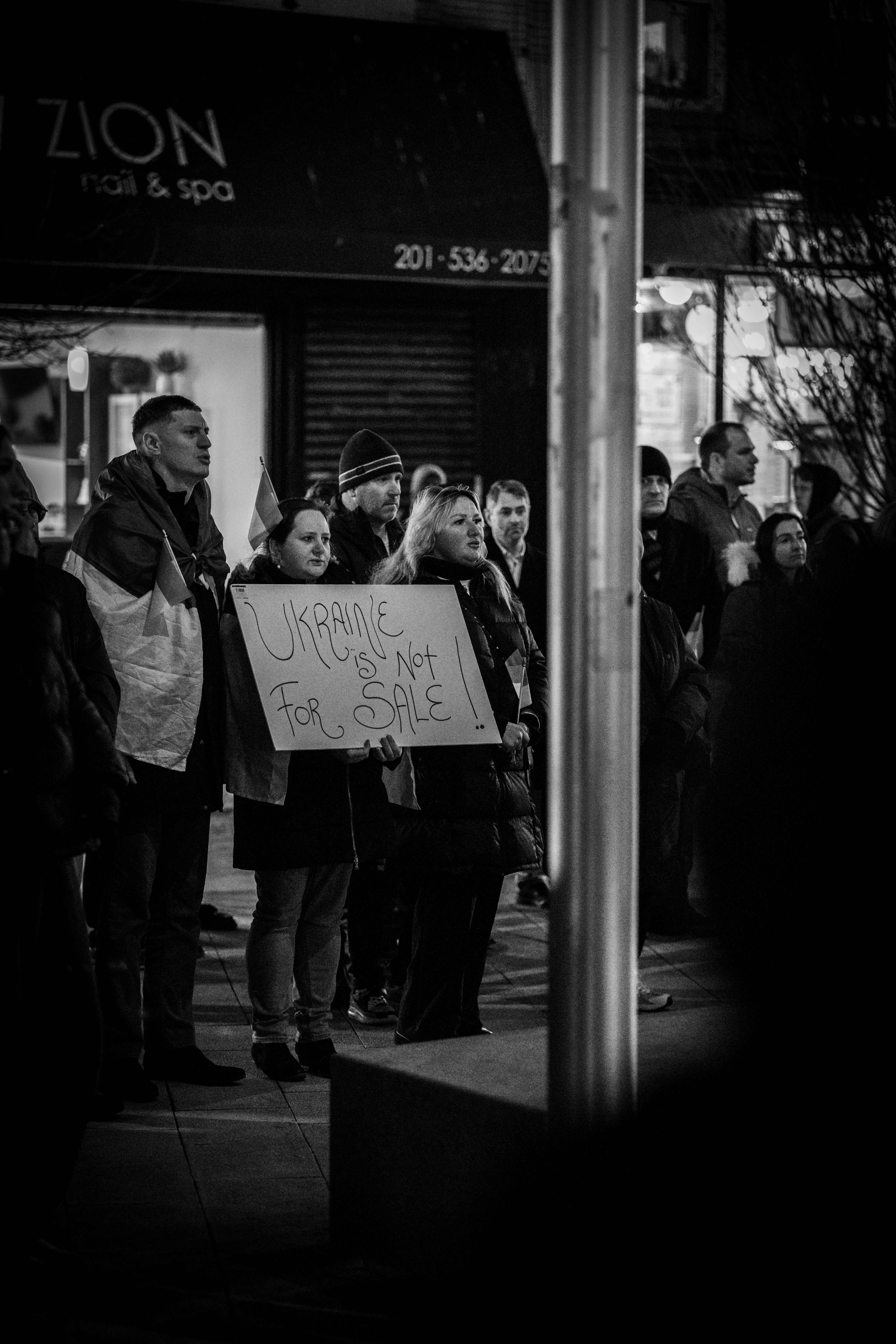 A group of people standing on a sidewalk holding a sign