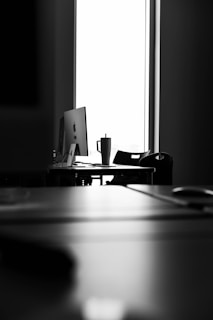 A black and white photo of a desk with a computer