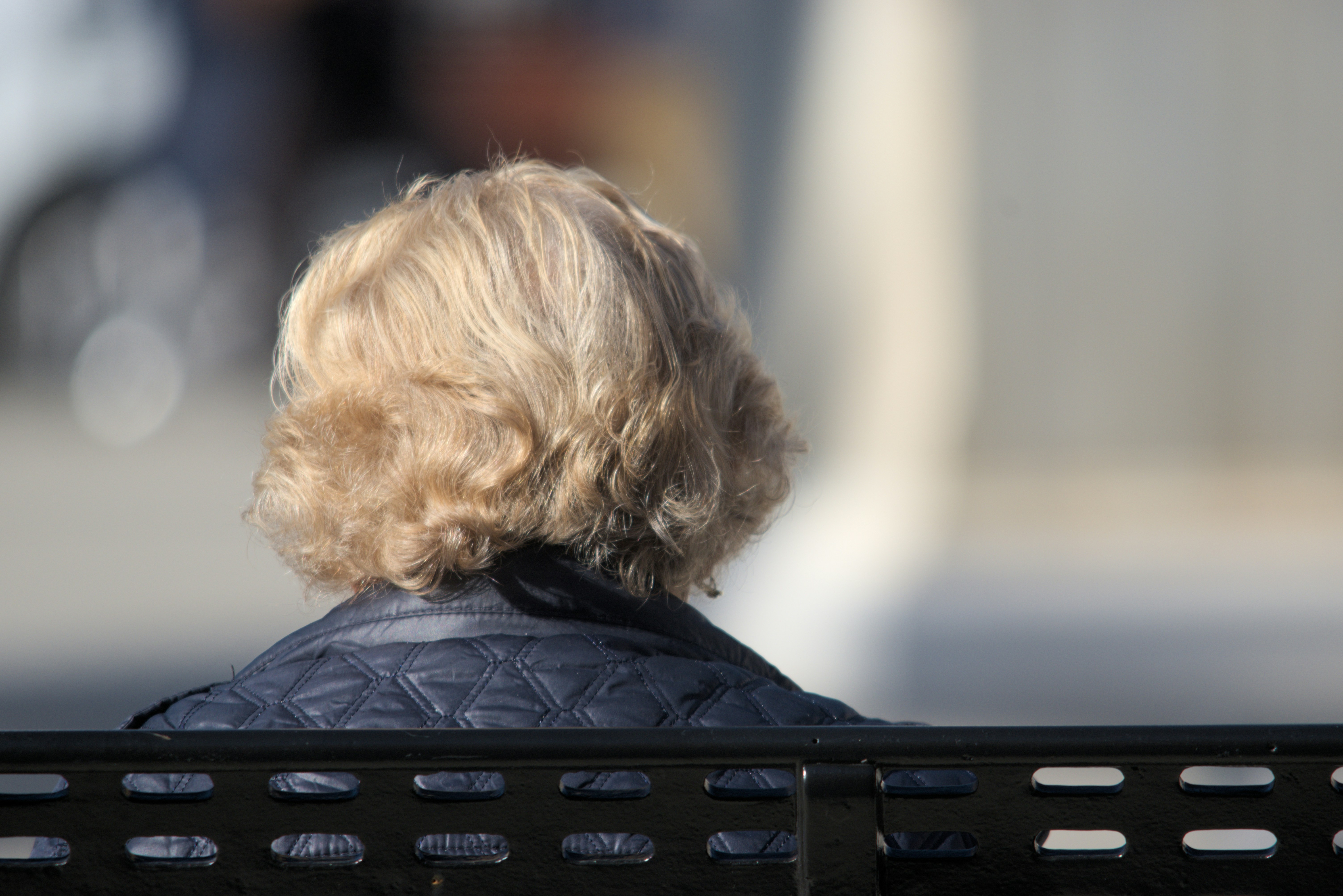 A woman sitting on a black bench with her back to the camera