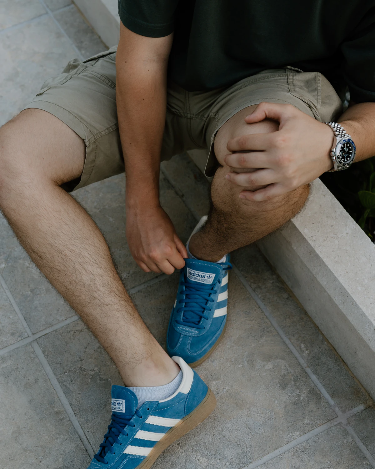 Man in his forties pausing while tying his shoes on a ledge, illustrating the morning joint stiffness and pain that can come with low testosterone.