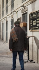 A man walking down a street next to a tall building