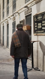 A man walking down a street next to a tall building
