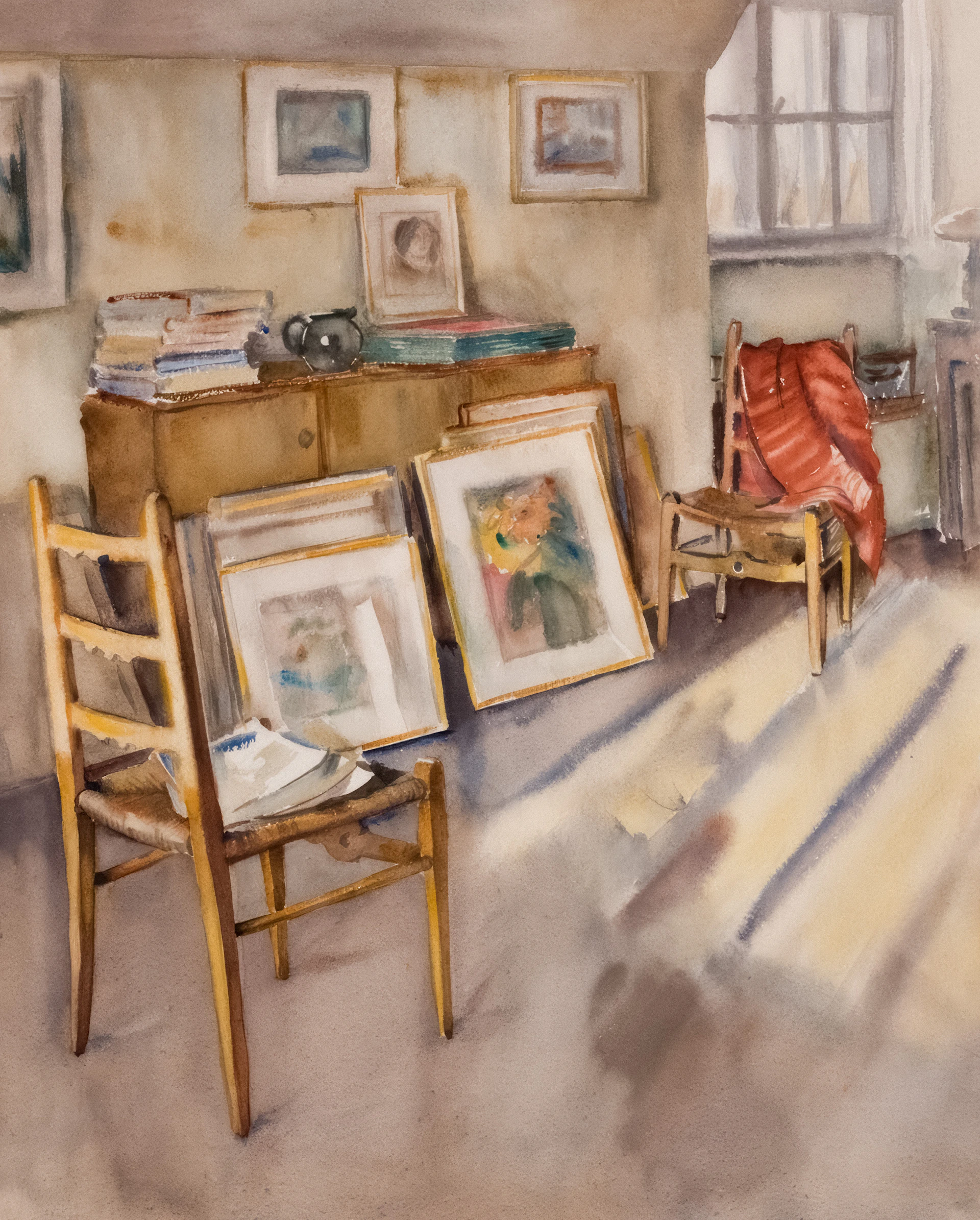 Sunlight streams into a room with artwork and chairs.