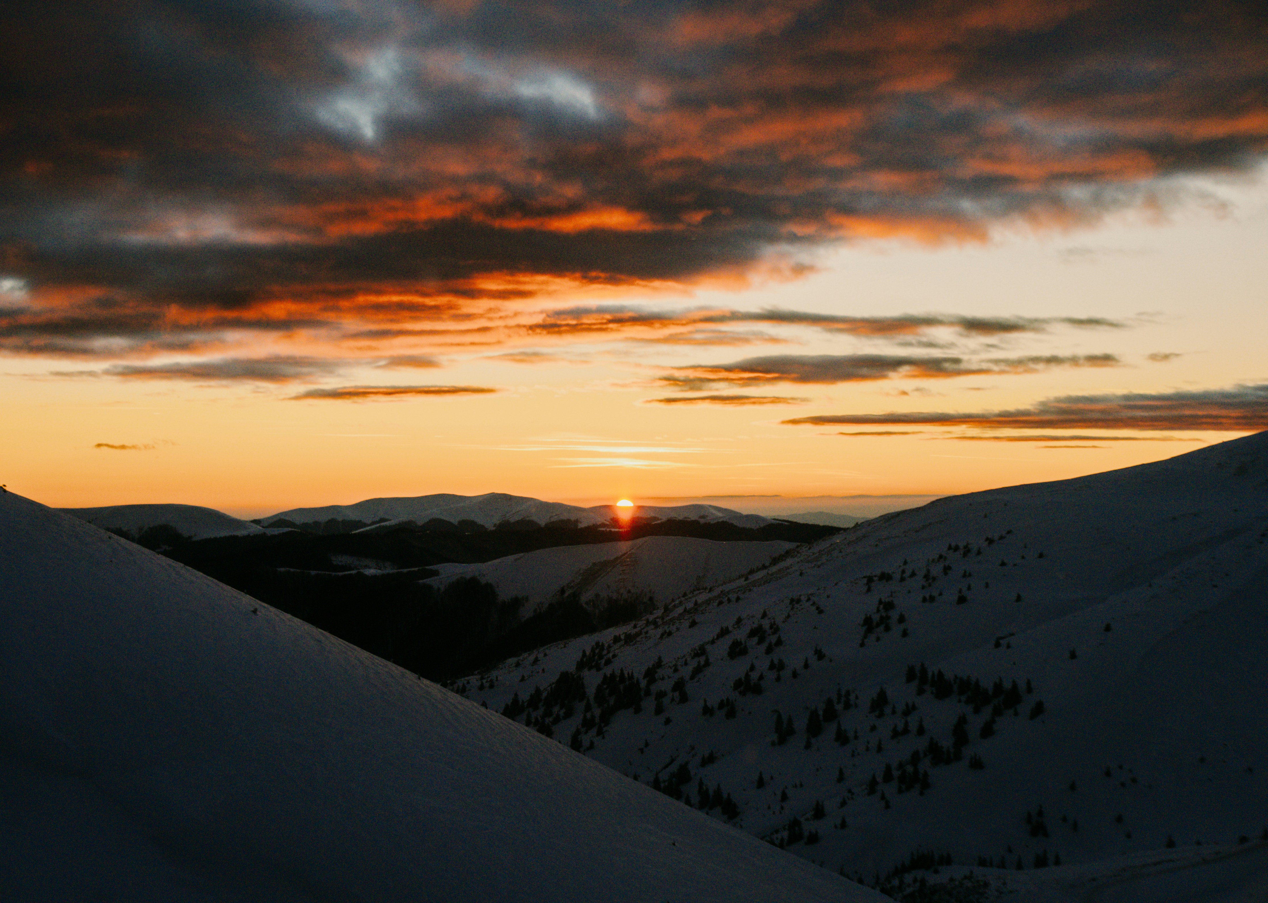 The sun is setting over a snowy mountain