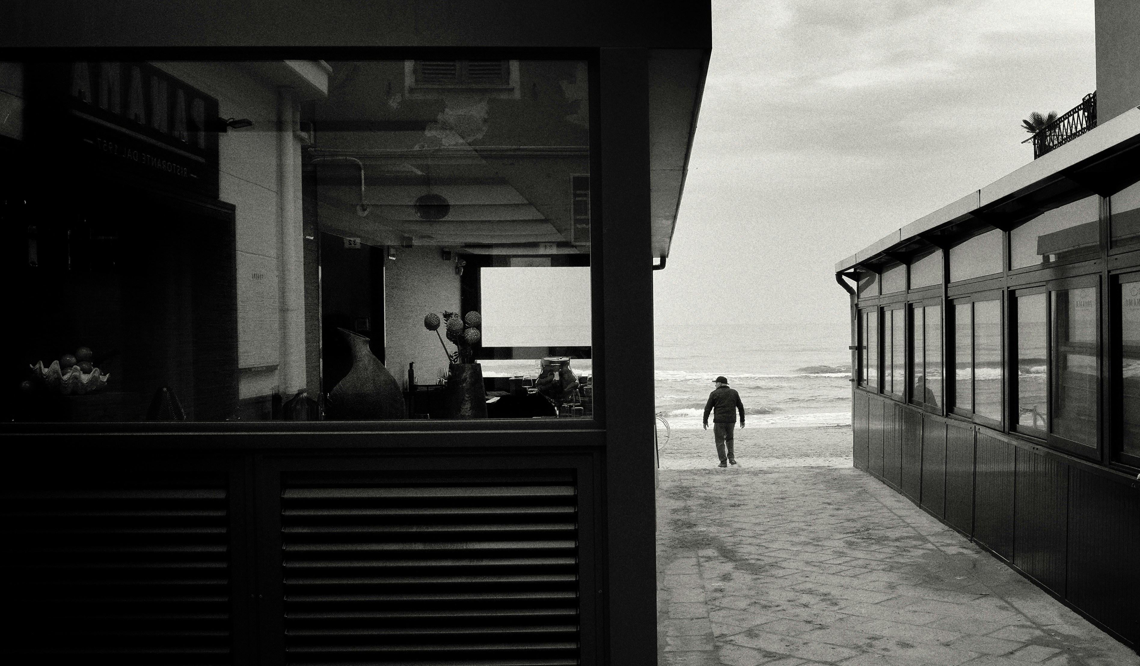 A black and white photo of a person walking on the beach