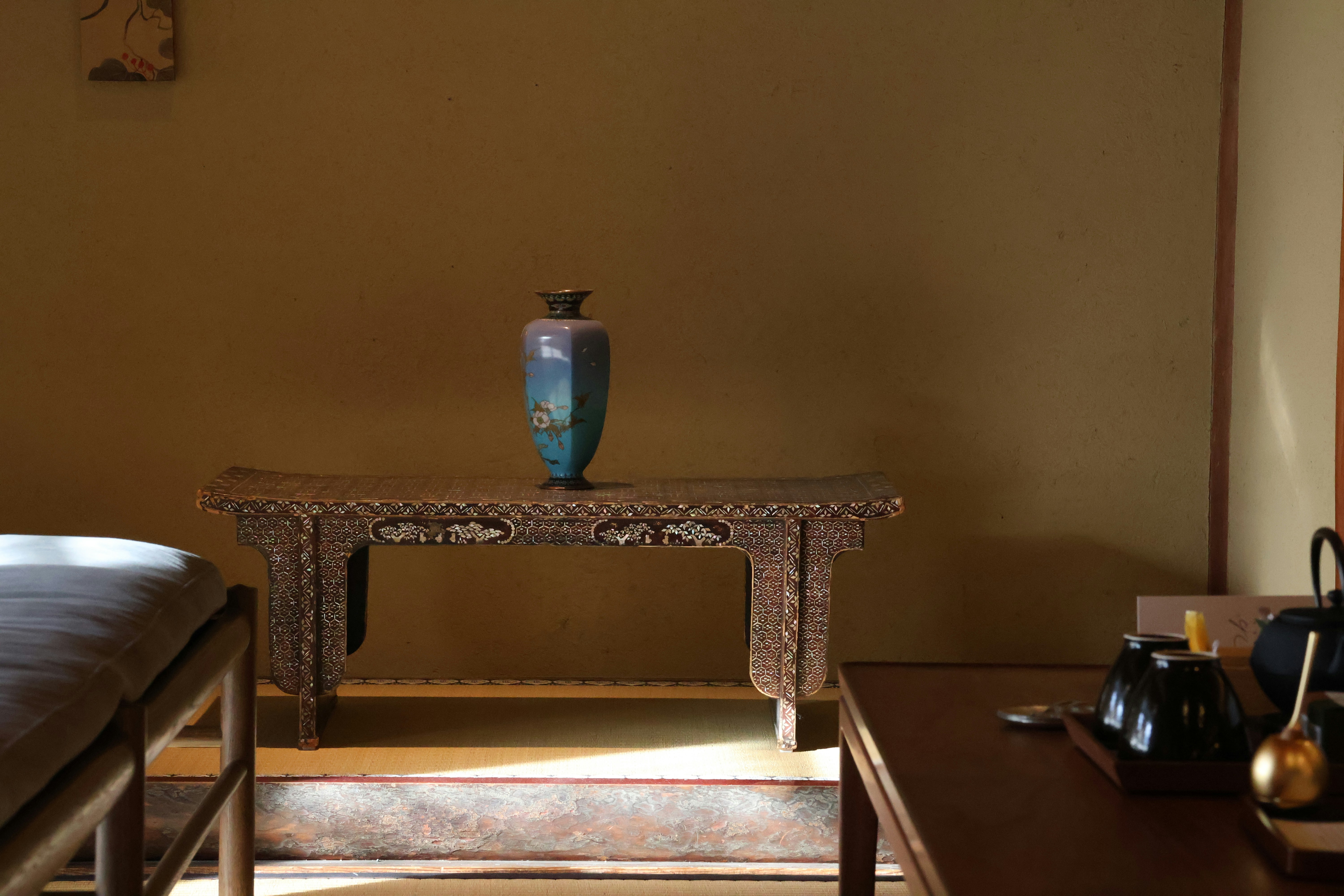 A room with a bed and a table with a vase on it