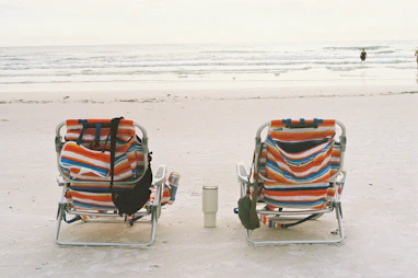 A couple of chairs sitting on top of a sandy beach