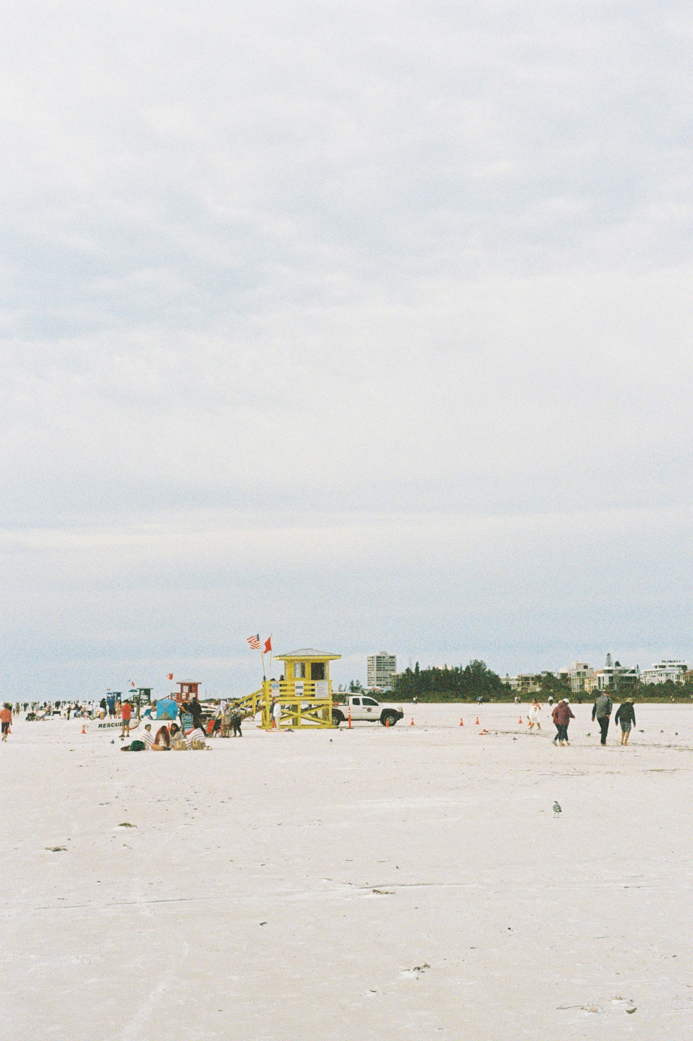 Un groupe de personnes debout au sommet d’une plage de sable