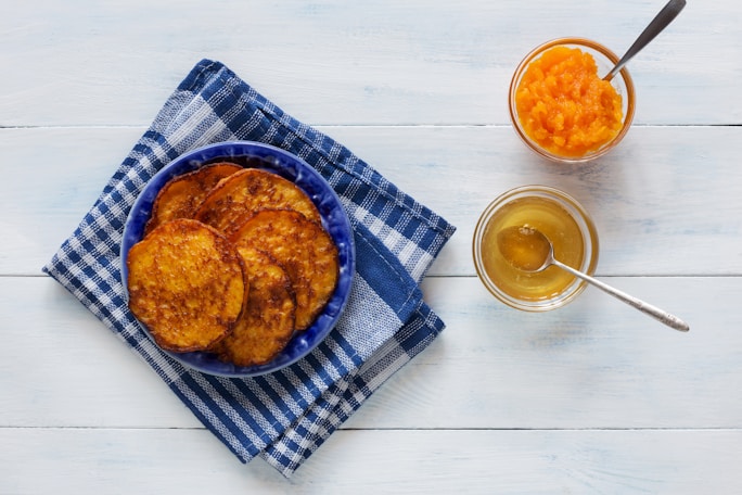 A blue plate topped with fried food next to two glasses of orange juice