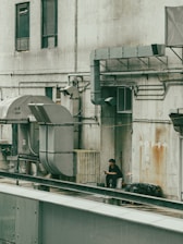 A man is sitting on a ledge next to a building