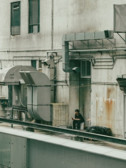 A man is sitting on a ledge next to a building