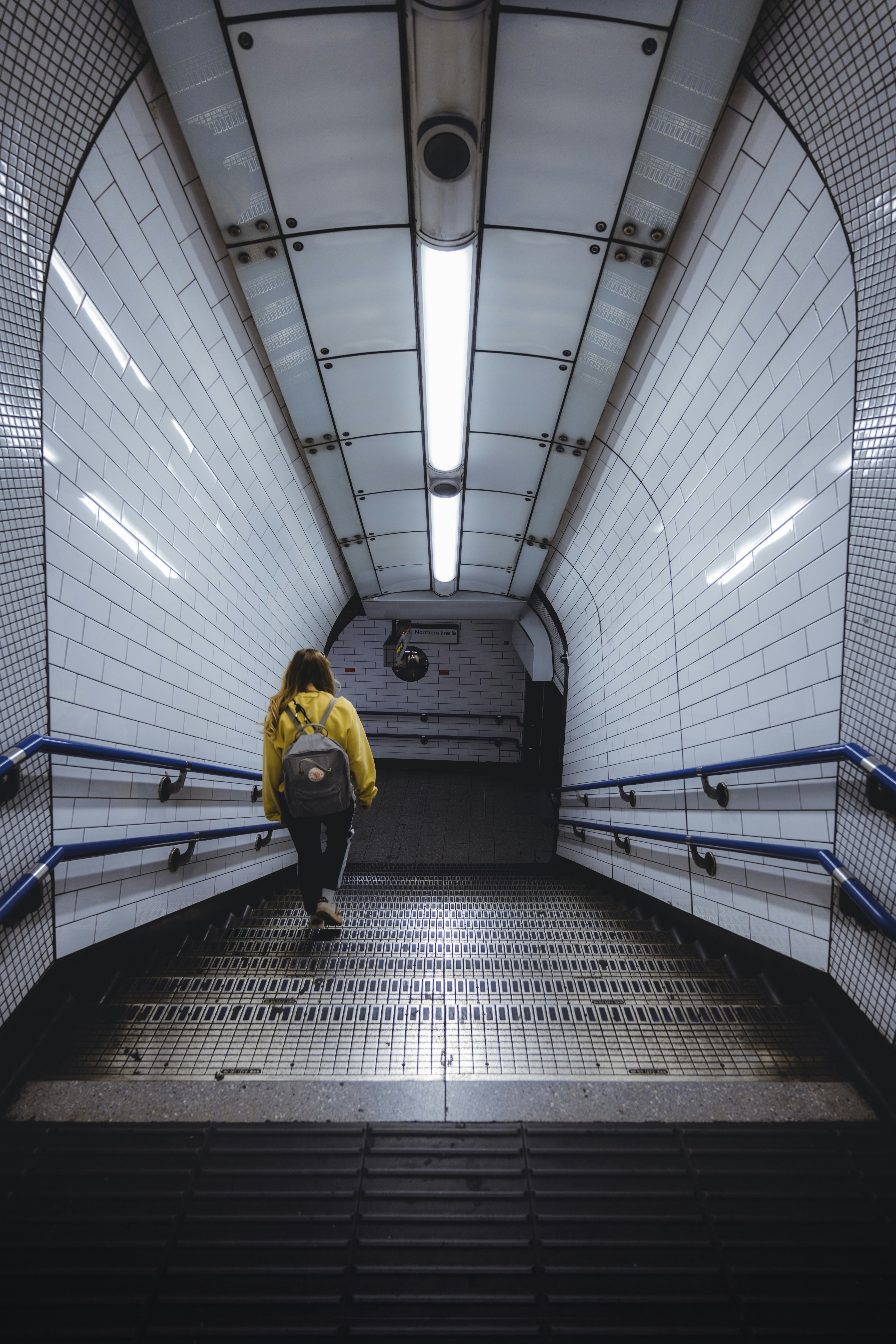 A person in a yellow jacket is sitting on an escalator