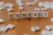 A wooden table topped with scrabble tiles spelling contact