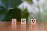 A wooden block spelling the word ipo on a table