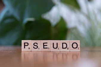 A scrabble block spelling the word ps seudo on a table