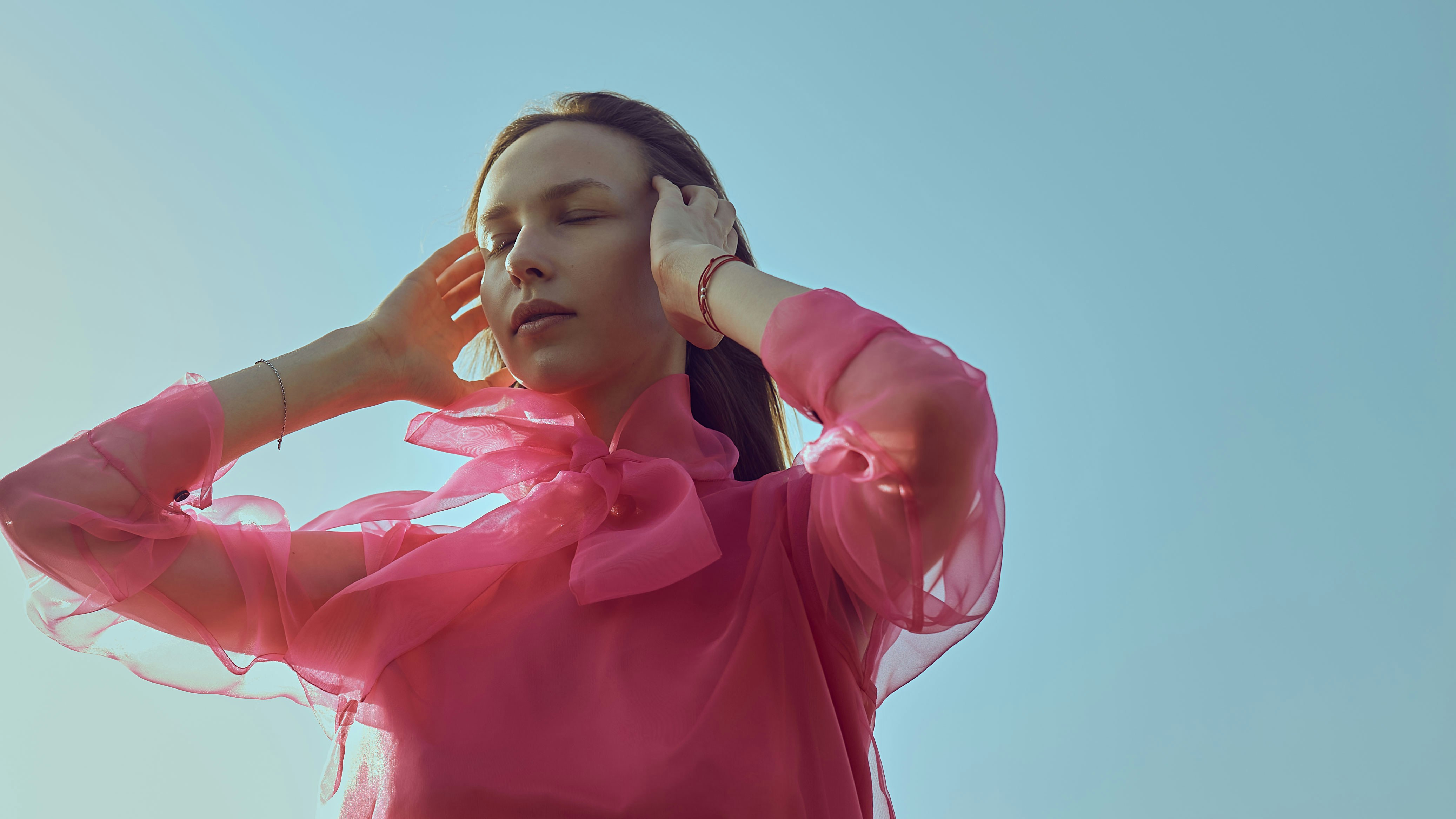 A woman in a pink top is holding her head