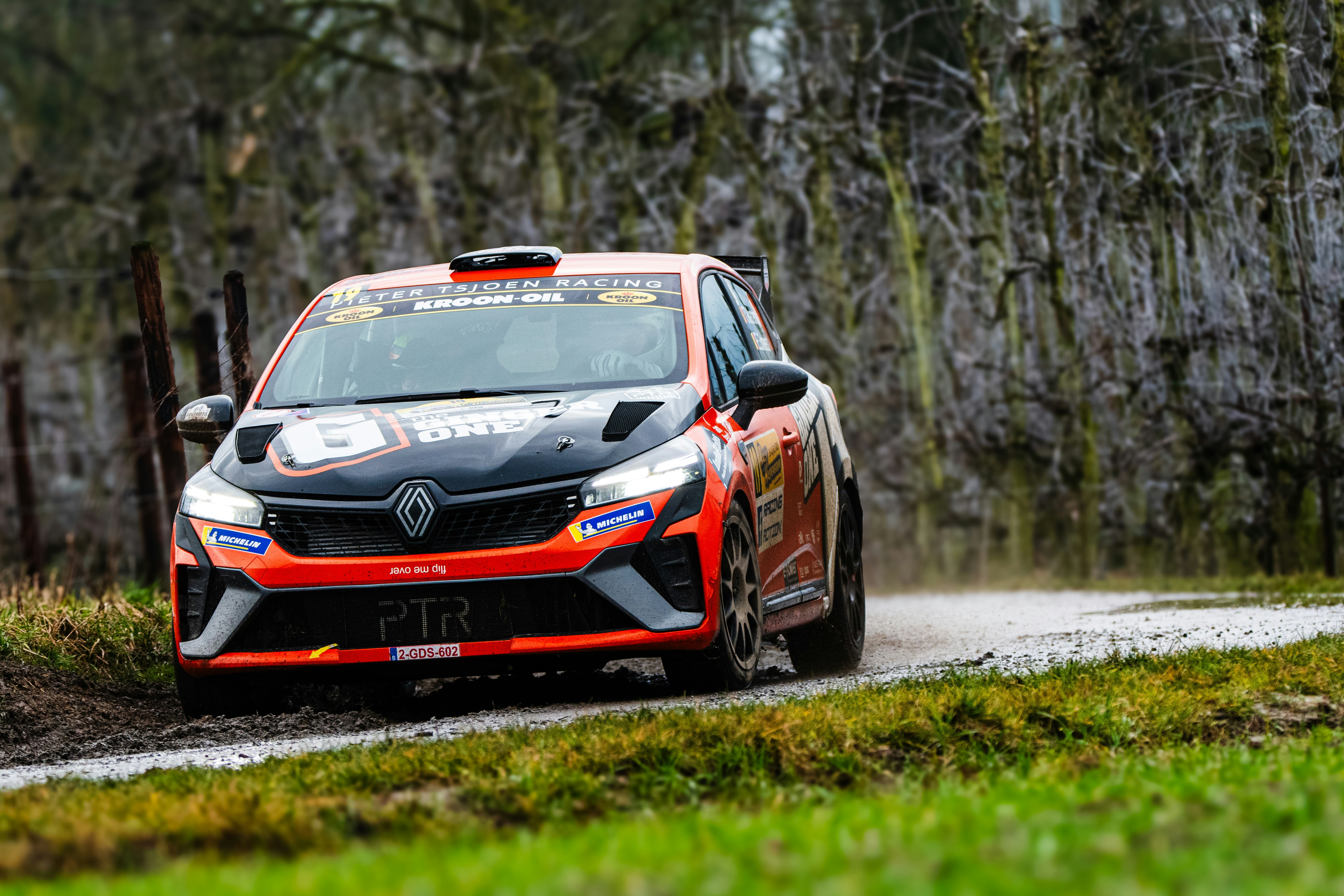 A red and black car driving down a dirt road