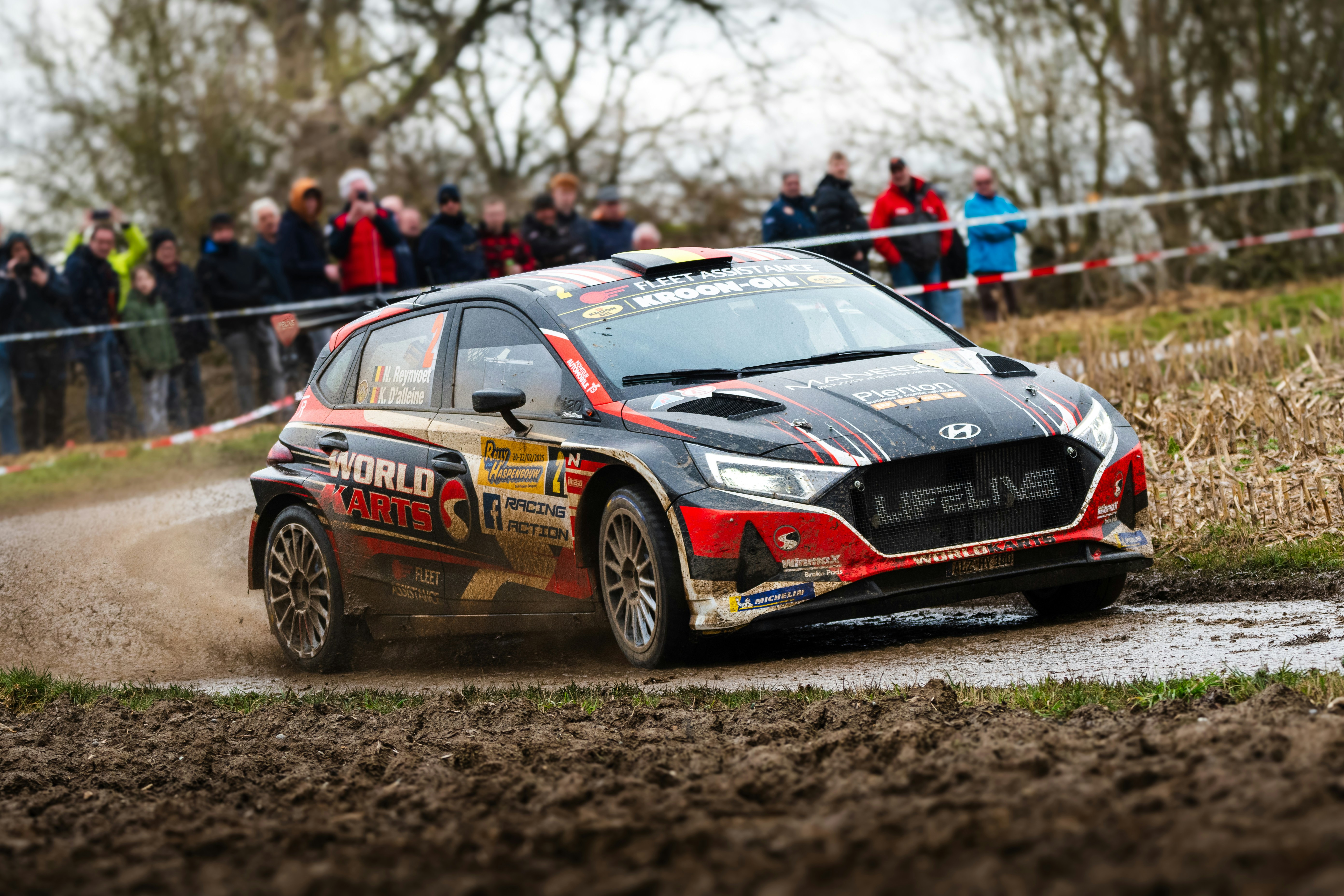 A car driving down a dirt road with people watching